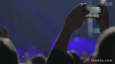 一名男子在流行音乐会上用智能手机拍摄表演歌手，其他歌迷<strong>鼓掌</strong>